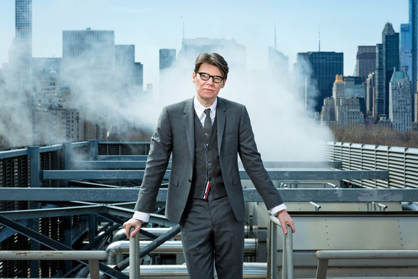 Andrew Bolton standing on a rooftop with the New York City skyline behind him.