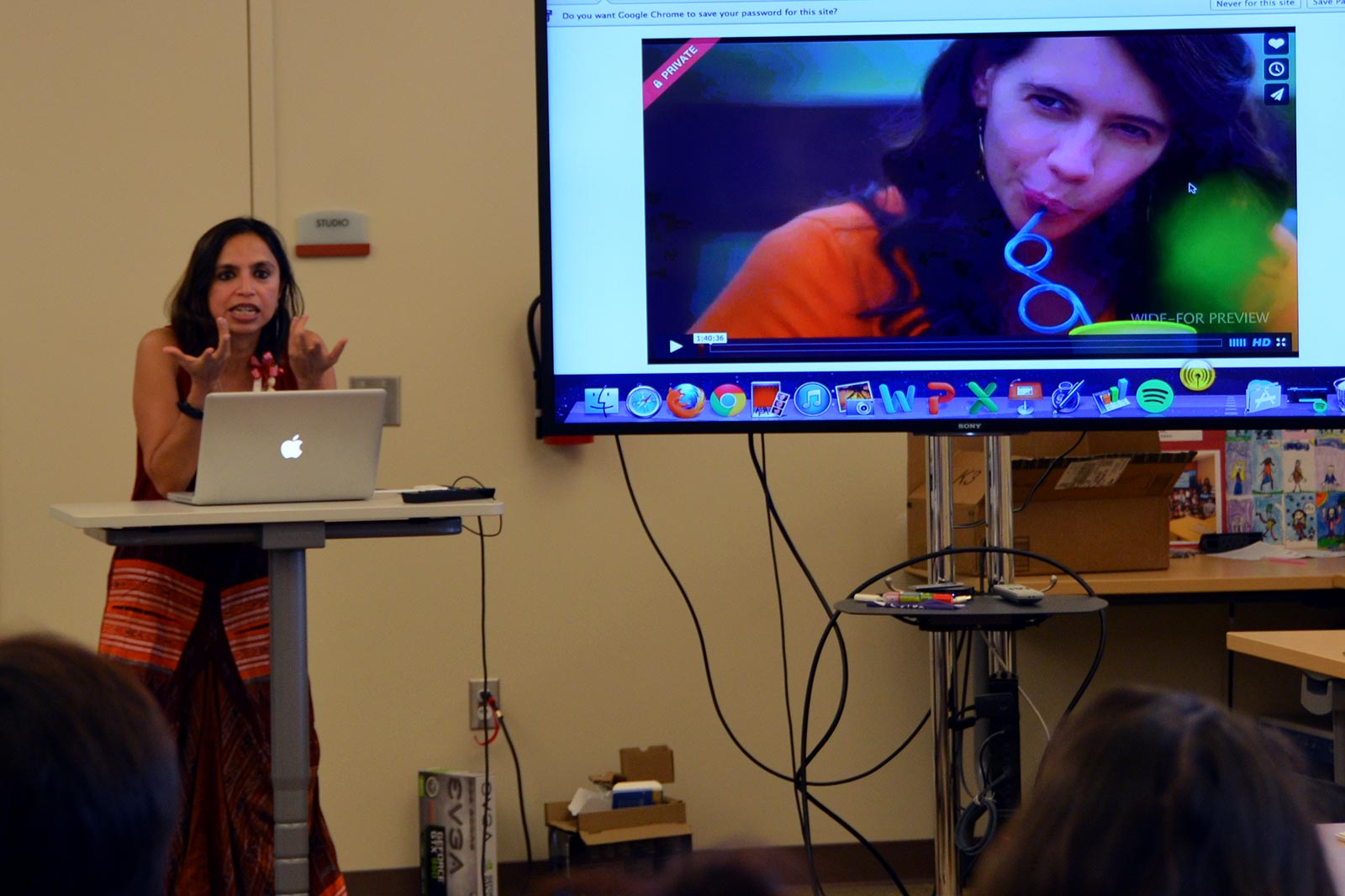 Shonali Bose speaks at a podium while presenting on a screen.